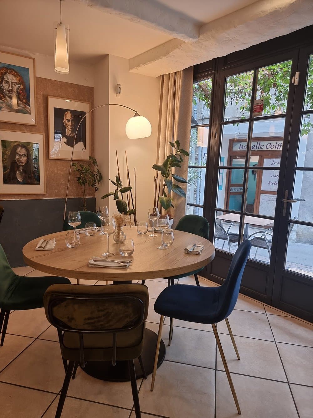 Table ronde dressée près de la fenêtre, sous les toiles de la galerie