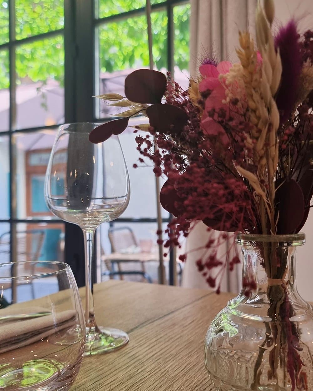 Table dressée avec bouquet de fleurs séchées devant la fenêtre